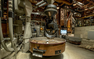 Two roasters produce small batch roasting, with beans whizzing in clear tubes through the space.