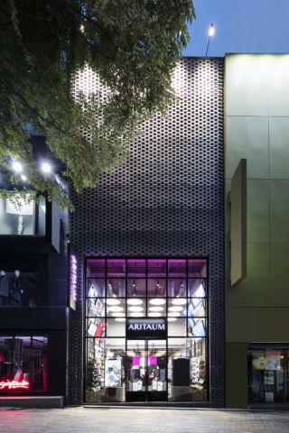 The exterior features 12m tall black brickwork with a splash of pink.