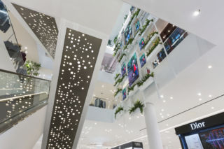 A triple-height atrium features greenery and screens for merchandising.