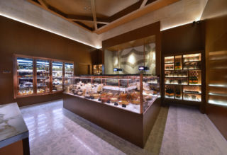 A custom copper and marble Deli counter displays cheeses, milk products and deli items. 