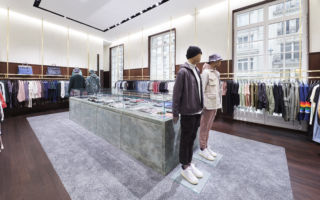 Bringing the classic and contemporary together; the menswear room features walnut panelling and brass clothing fixtures which surround a monumental, custom marble display case. 